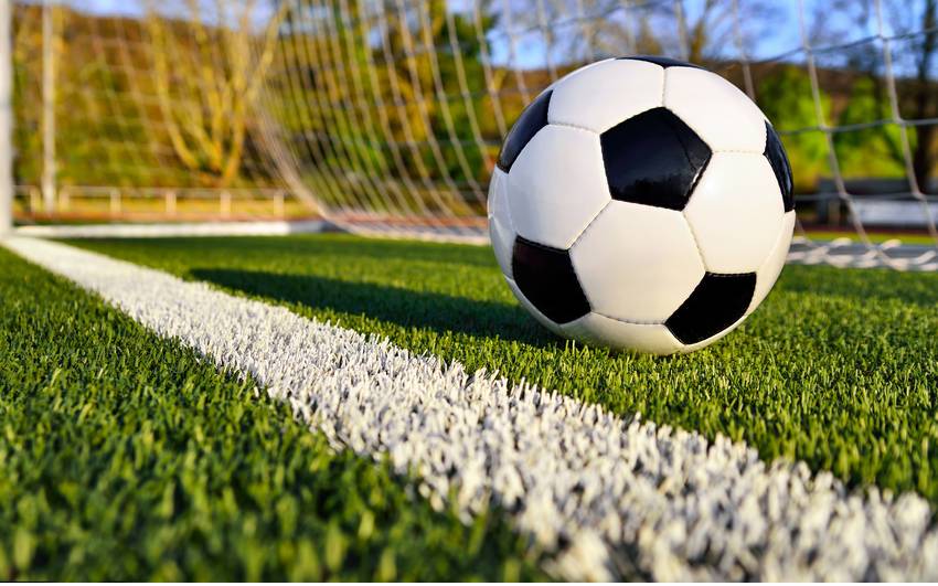 Ein Fußball liegt im Tor eines Fußballfeldes.