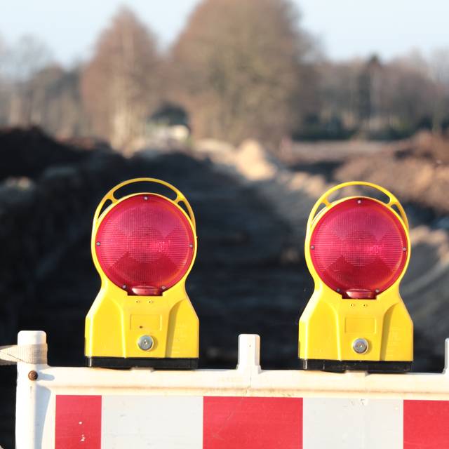 Eine Straßensperre steht im Vordergrund des Bilds, im Hintergrund sieht man unscharf die Baustelle einer neuen Straße.