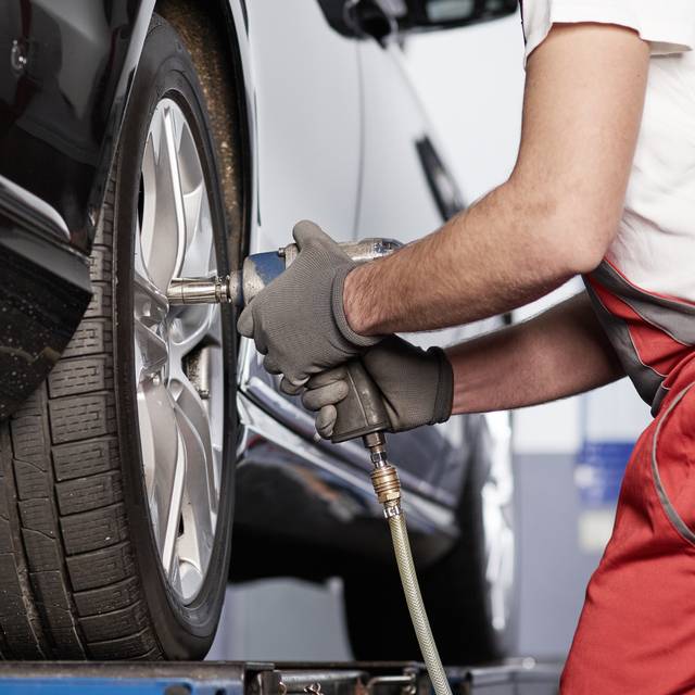 Ein Mechaniker beim Radwechsel (Symbolbild).