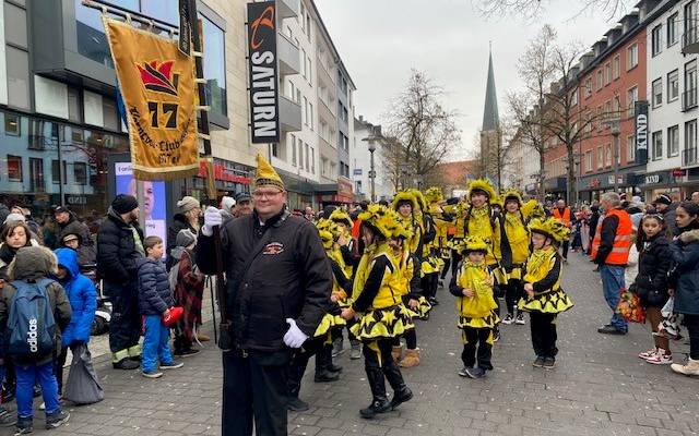Eine Kindertanzgruppe mit mehreren Erwachsenen trägt schwarz-gelbe Kostüme.