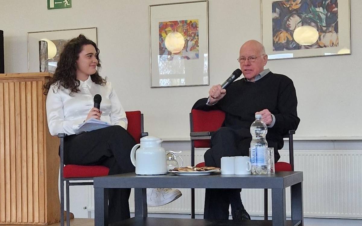 Auf dem Bild ist ehemaliger Bundespräsident Norbert Lammert mit einer Schülerin des Christian Rohlf Gymnasiums zu sehen, die sich mit MIkrofonen in der Hand auf einer Bühne in der Aula der Schule unterhalten.