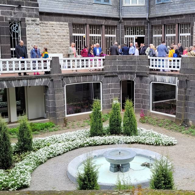 Zu sehen ist die Villa Hohenhof von der Außenansicht sowie verschiedene Menschen, die zur Einweihung erschienen sind