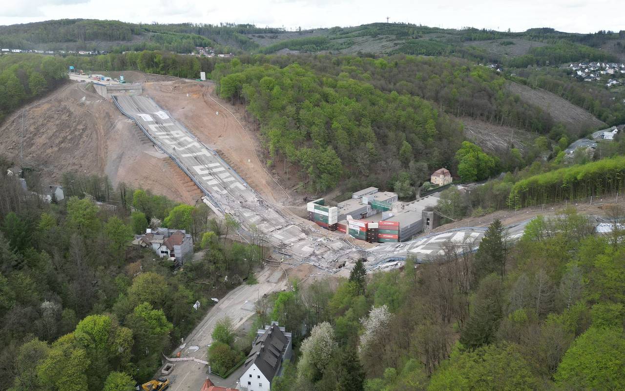 Gesprengte Brücke. Brückenteile liegen auf der Erde. Auf den Teilen steht der Spruch "Lasst uns Brücken bauen".