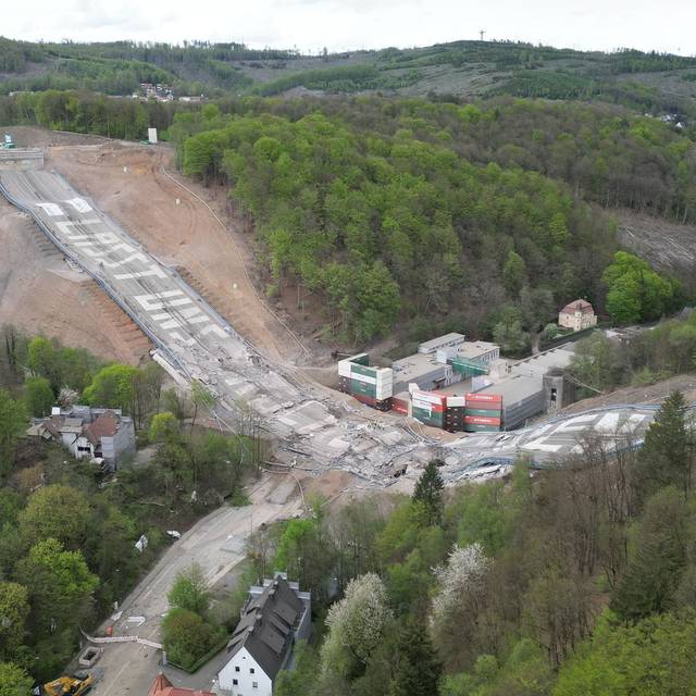 Gesprengte Brücke. Brückenteile liegen auf der Erde. Auf den Teilen steht der Spruch "Lasst uns Brücken bauen".