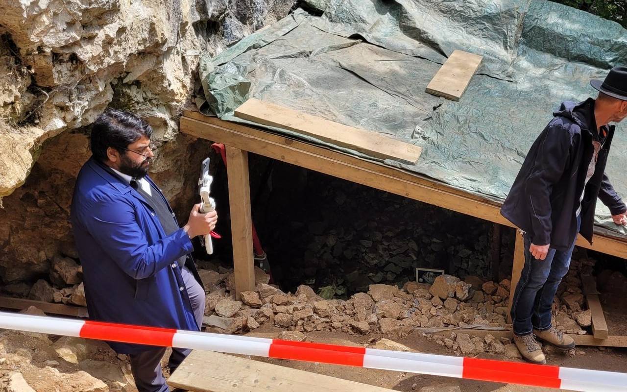 Zu sehen sind Archäologen an der Blätterhöhle, auf einer Plane sind zudem Pläne sowie die archäologischen Funde aus der Höhle zu sehen.