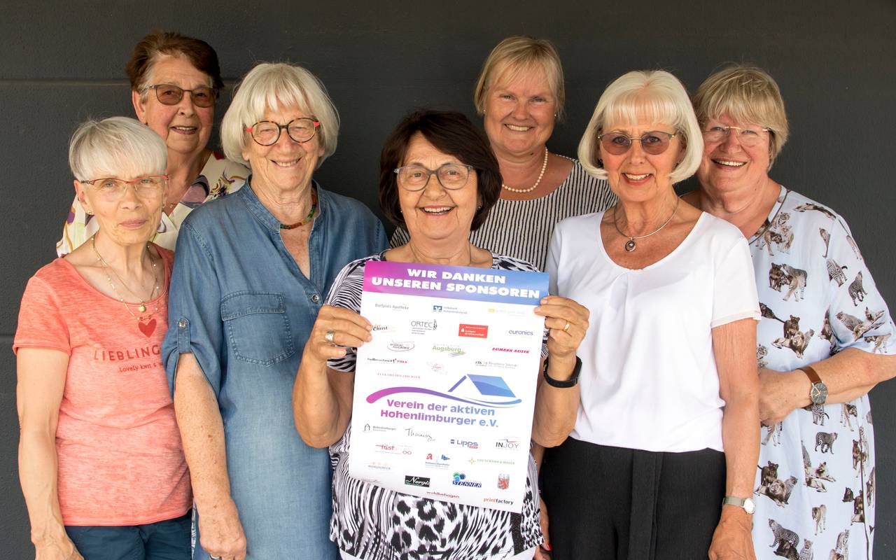 Sieben Frauen stehen in zwei Reihen und schauen in die Kamera