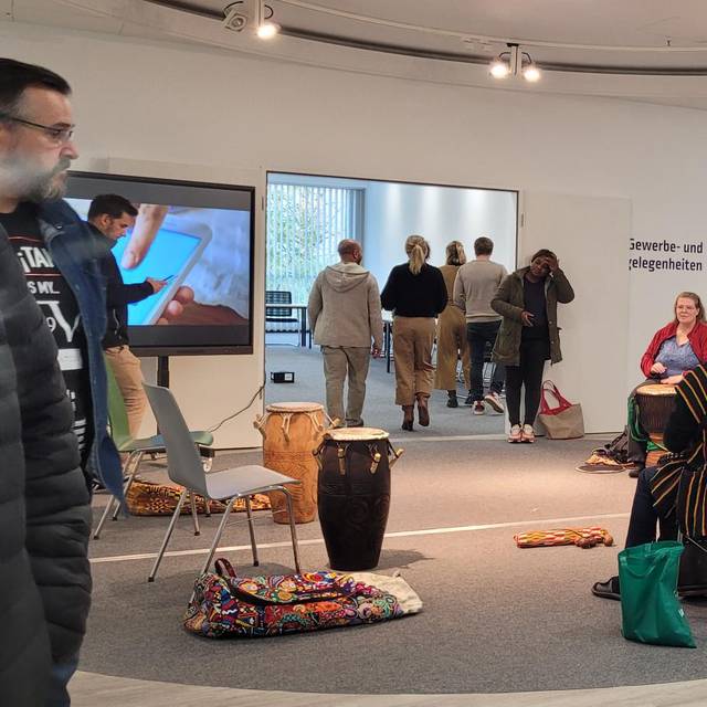 Zu sehen sind Leute in einem Sitzkreis, die auf Trommeln spielen, im neuen Volme-Forum, im Rahmen eines Workshops.