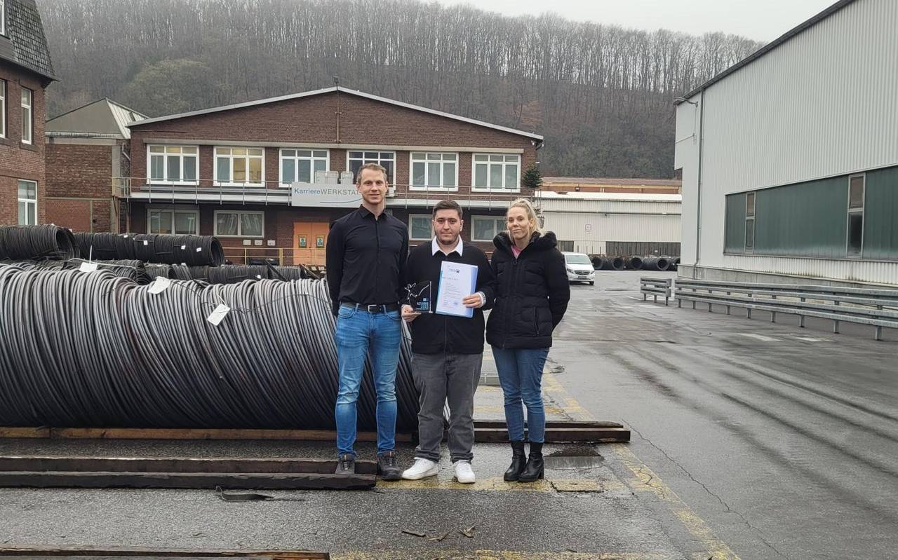 Zu sehen sind 3 Leute vor Stahldrähten bei den Deutschen Edelstahlwerken. Darunter der Ausbildungsleiter Kristian Baum, Vertreterin des Ausbildungsrates und der Azubi Bora Turan, der seinen Preis hält.