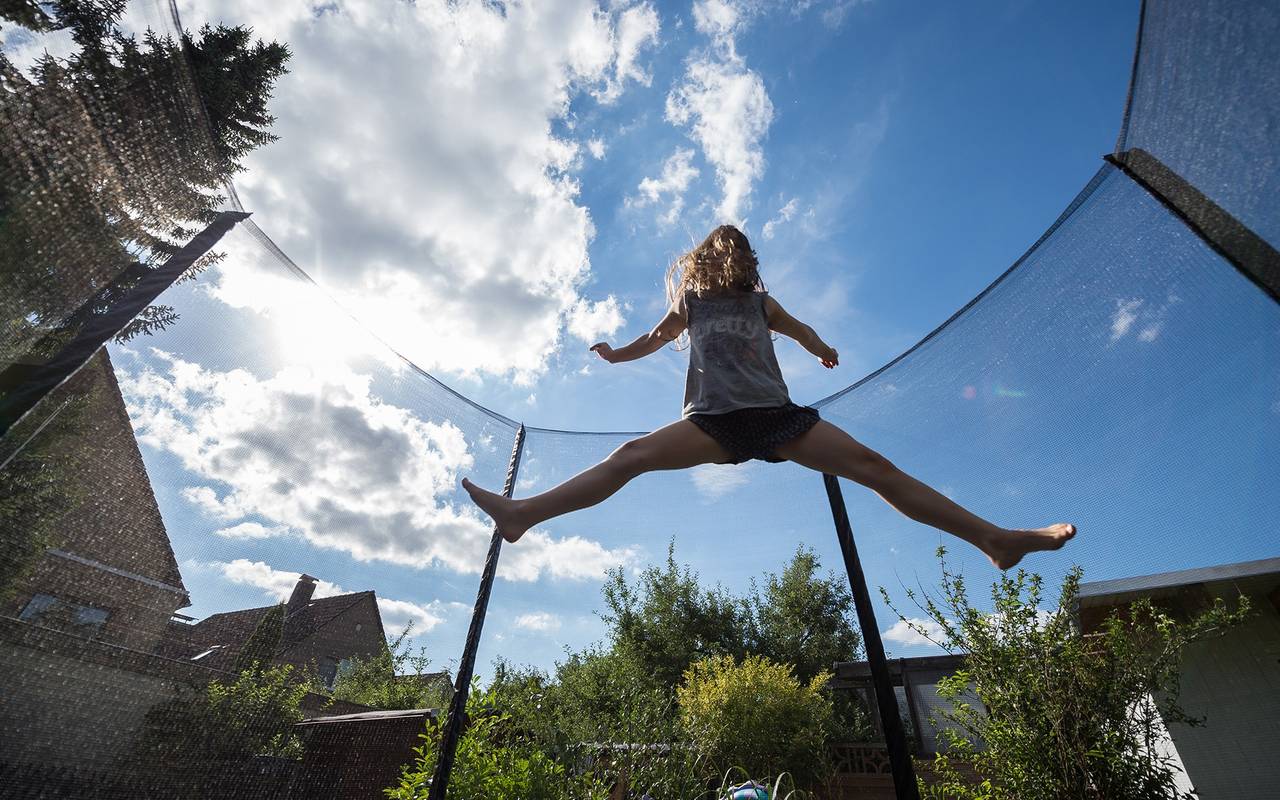 Ein Mädchen springt in einem Garten auf einem Trampolin
