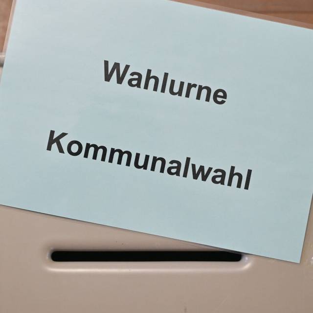 Ein Zettel mit der Aufschrift "Wahlurne Kommunalwahl" liegt auf einer Wahlurne in einem Wahllokal.