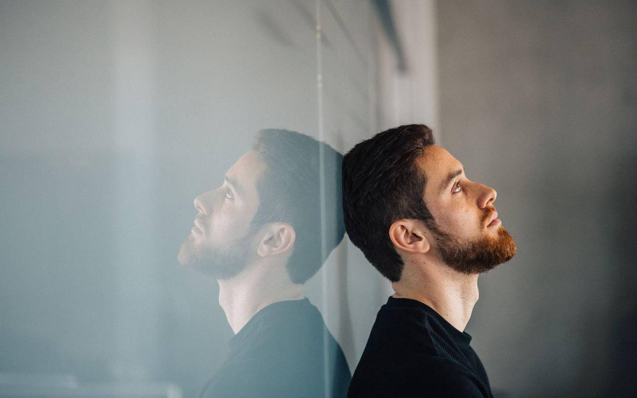 Ein junger Mann lehnt nachdenklich an einer Glaswand