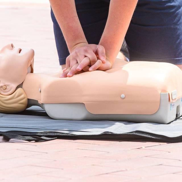 Eine Person übt eine Herzdruckmassage an einer Erste-Hilfe-Puppe