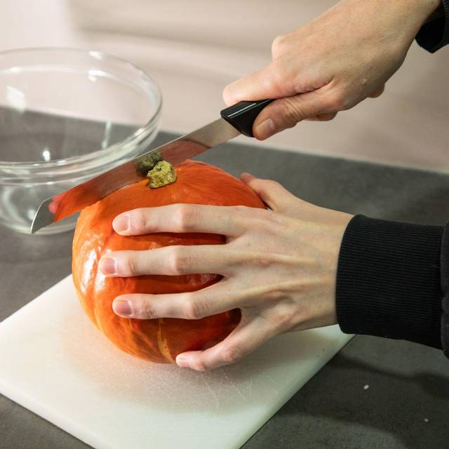 Frau schneidet einen Kürbis