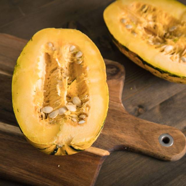 Ein aufgeschnittener Spaghetti-Kürbis liegt auf einem Brett