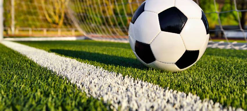 Ein Fußball liegt im Tor eines Fußballfeldes.