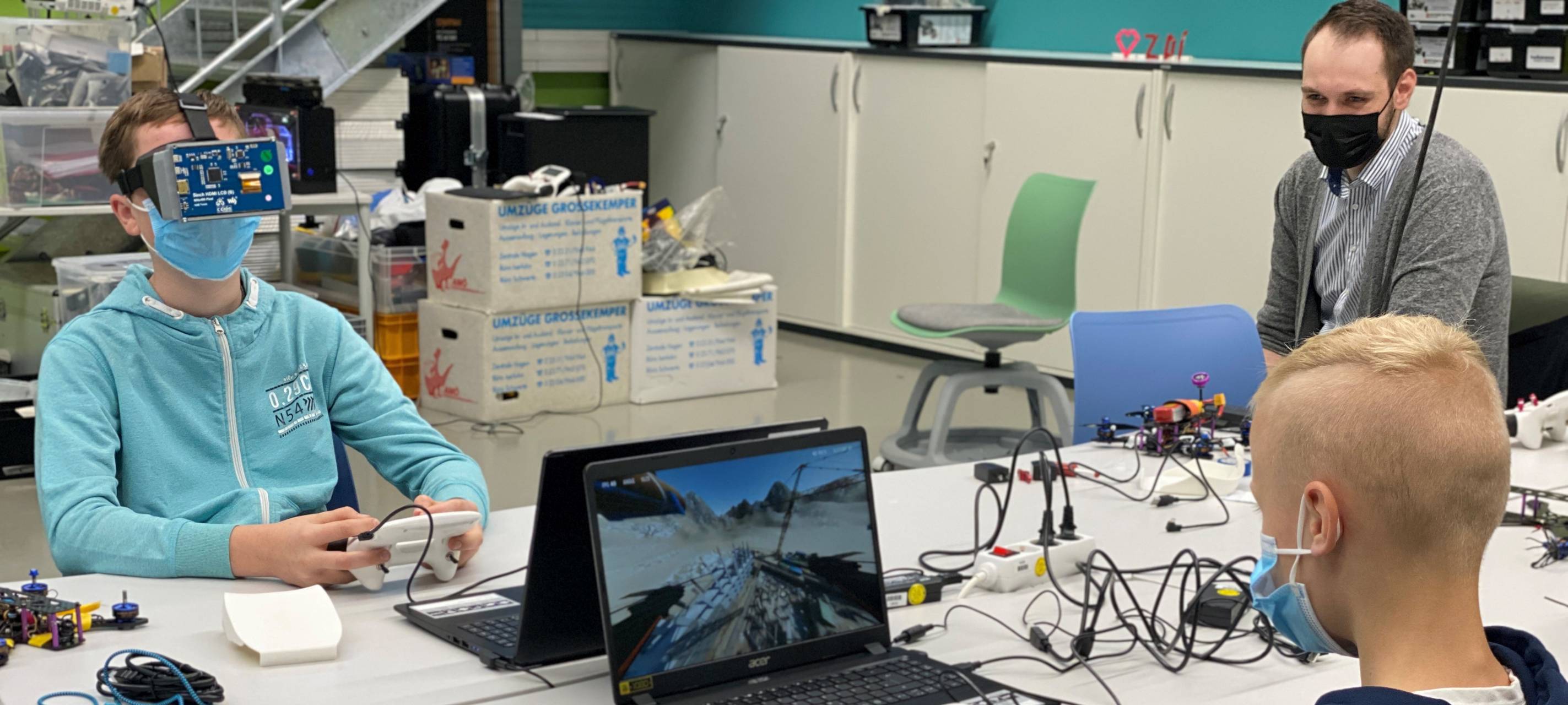Jugendliche sitzen am Computer und simulieren Drohnenflüge.