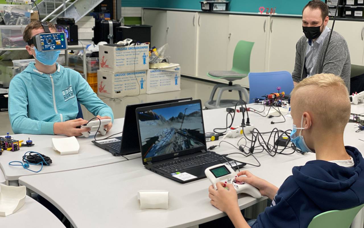 Jugendliche sitzen am Computer und simulieren Drohnenflüge.
