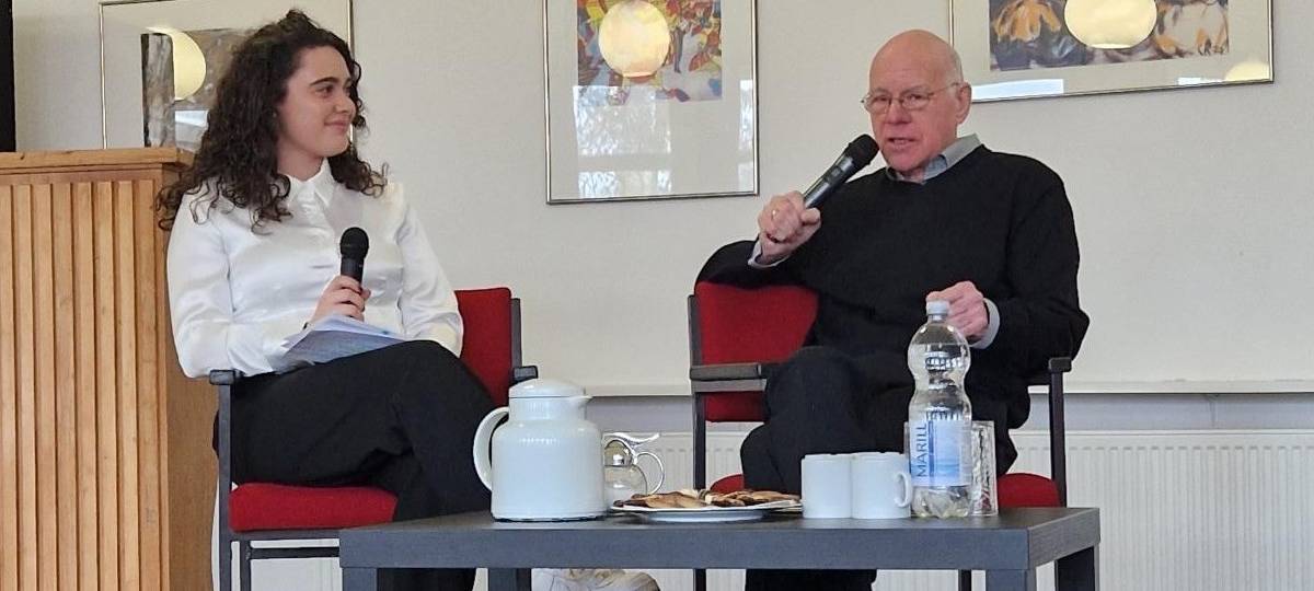 Auf dem Bild ist ehemaliger Bundespräsident Norbert Lammert mit einer Schülerin des Christian Rohlf Gymnasiums zu sehen, die sich mit MIkrofonen in der Hand auf einer Bühne in der Aula der Schule unterhalten.