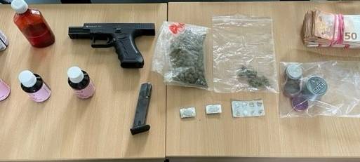 Waffe, Drogen und Tabletten auf einem Tisch.