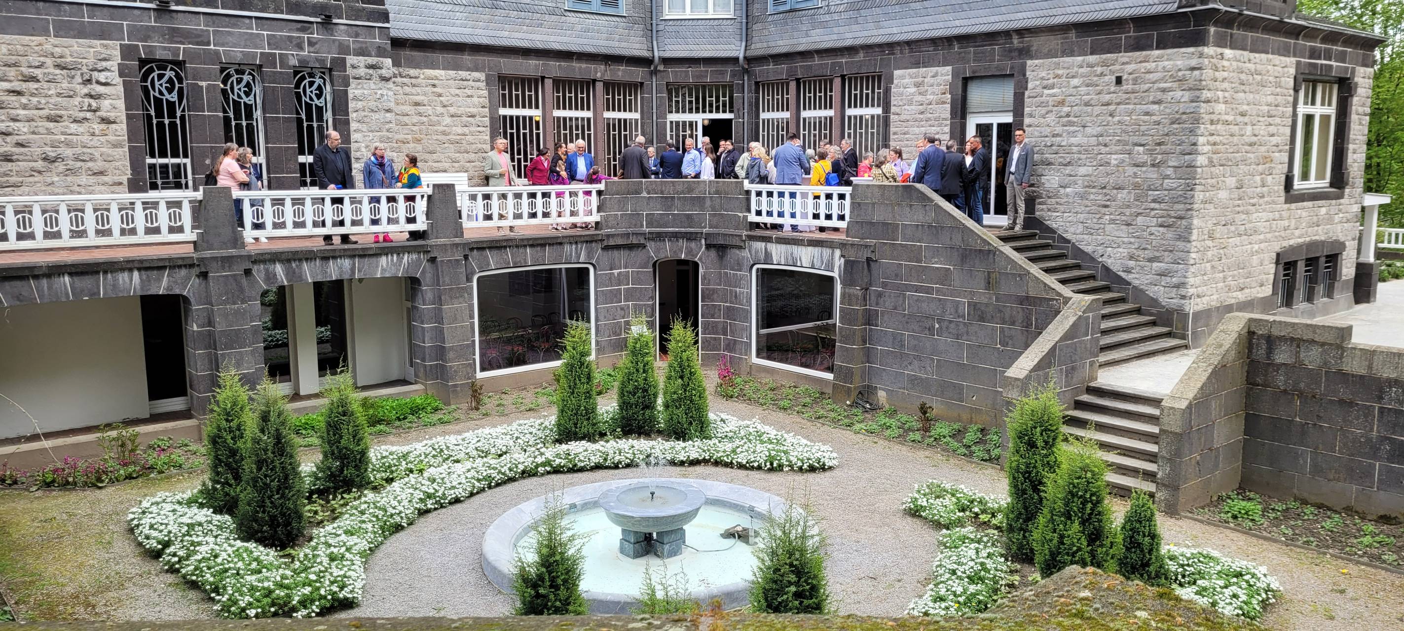 Zu sehen ist die Villa Hohenhof von der Außenansicht sowie verschiedene Menschen, die zur Einweihung erschienen sind