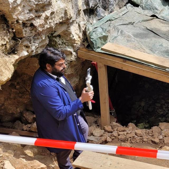 Zu sehen sind Archäologen an der Blätterhöhle, auf einer Plane sind zudem Pläne sowie die archäologischen Funde aus der Höhle zu sehen.
