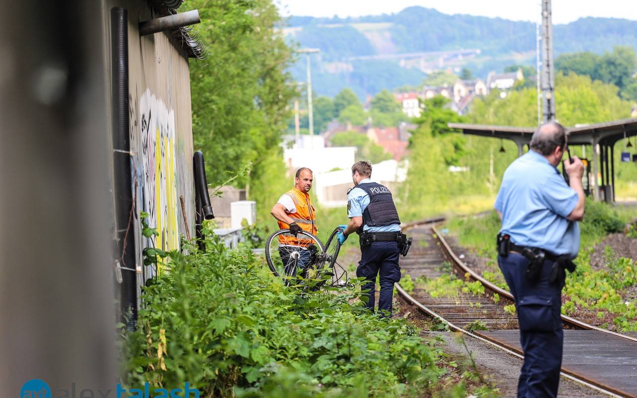 Ein Polizist und ein Mitarbeiter der Deutschen Bahn haben ein Fahrrad in der Hand. Sie tragen es von den Bahngleisen herunter.