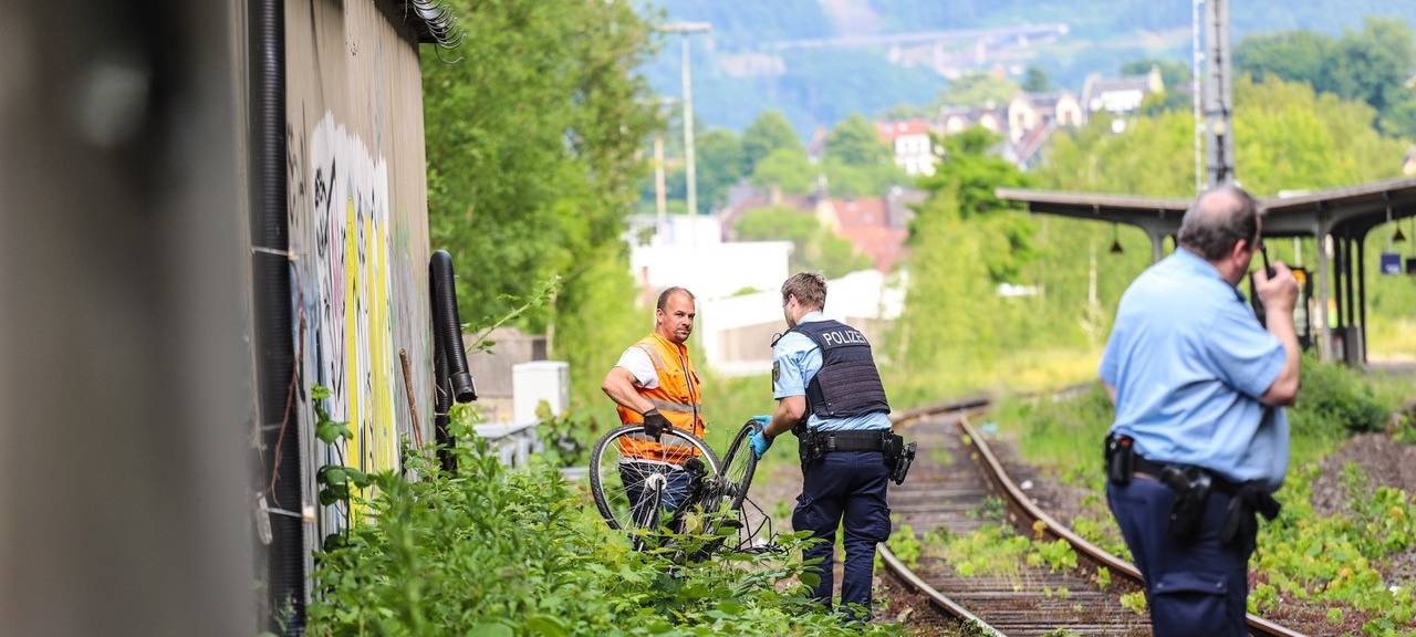 Ein Polizist und ein Mitarbeiter der Deutschen Bahn haben ein Fahrrad in der Hand. Sie tragen es von den Bahngleisen herunter.