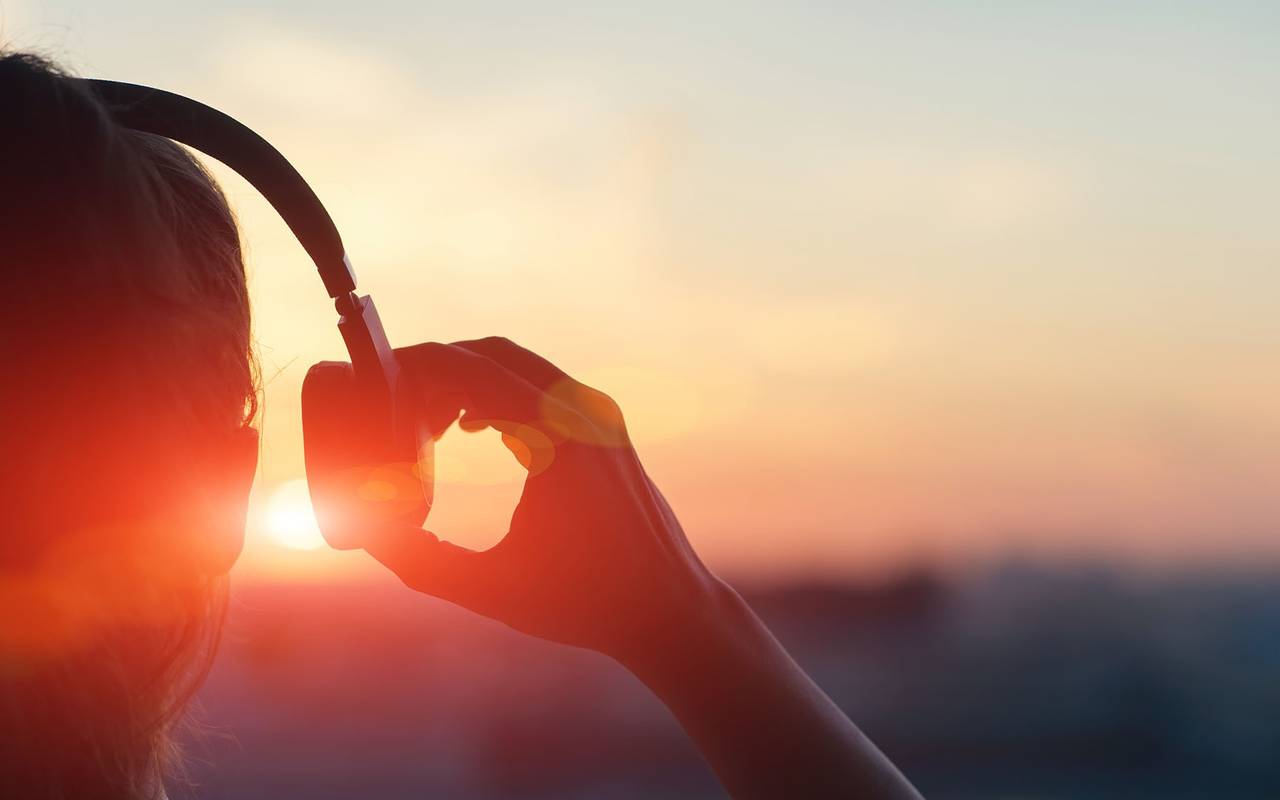 Frau mit Kopfhörern vor Sonnenuntergang