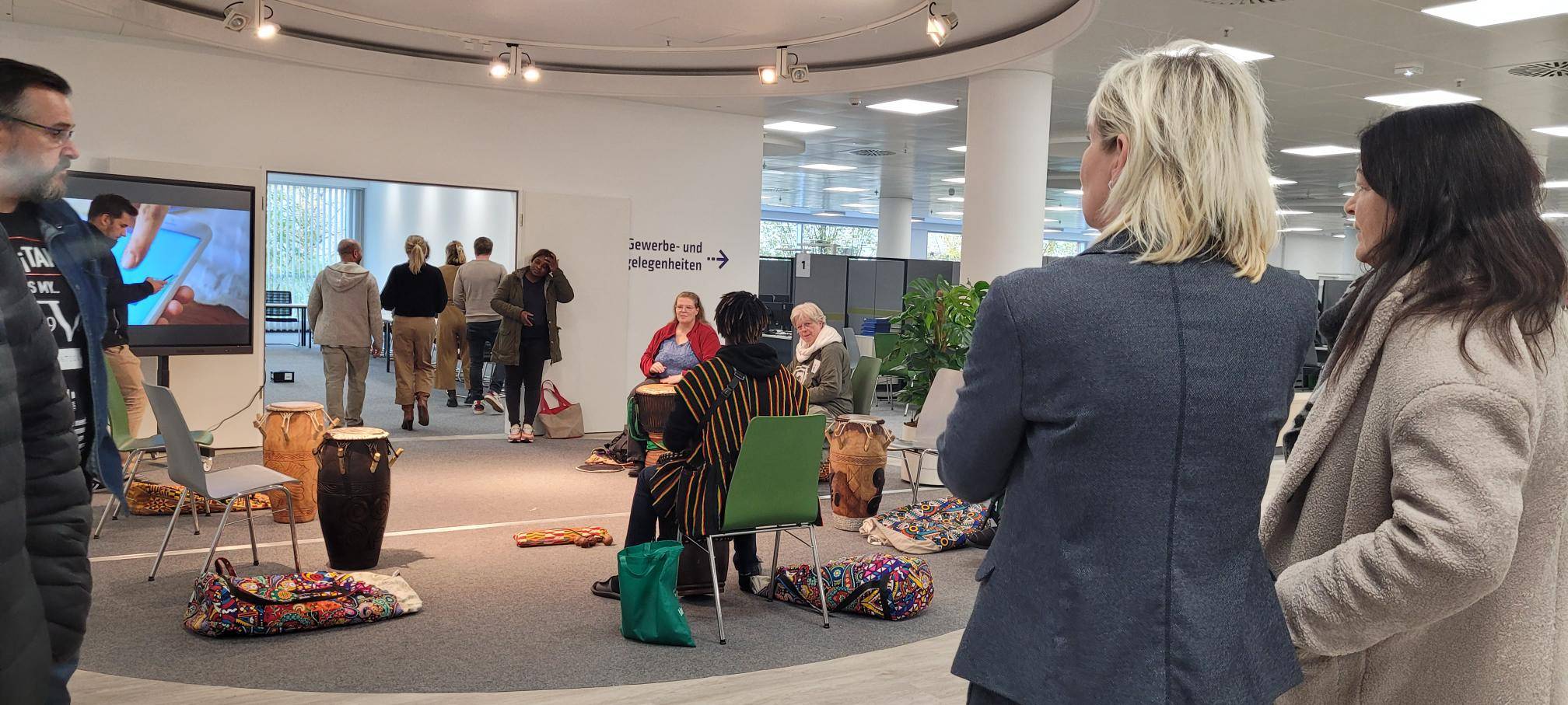 Zu sehen sind Leute in einem Sitzkreis, die auf Trommeln spielen, im neuen Volme-Forum, im Rahmen eines Workshops.