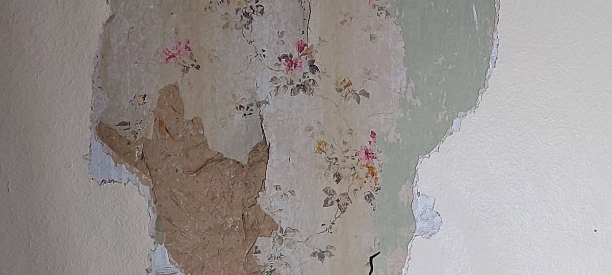 Unter den Farbschichten kommen alte Tapeten zum Vorschein.