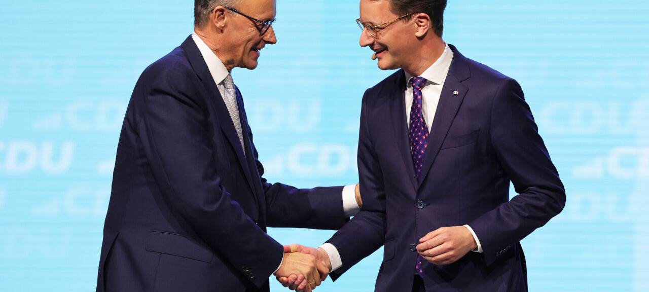 Friedrich Merz (l), CDU-Bundesvorsitzender und Unions-Kanzlerkandidat, und Hendrik Wüst (CDU), Ministerpräsident von Nordrhein-Westfalen, geben sich bei einer Wahlkampfveranstaltung der CDU in der Rudolf Weber-Arena auf der Bühne die Hand.