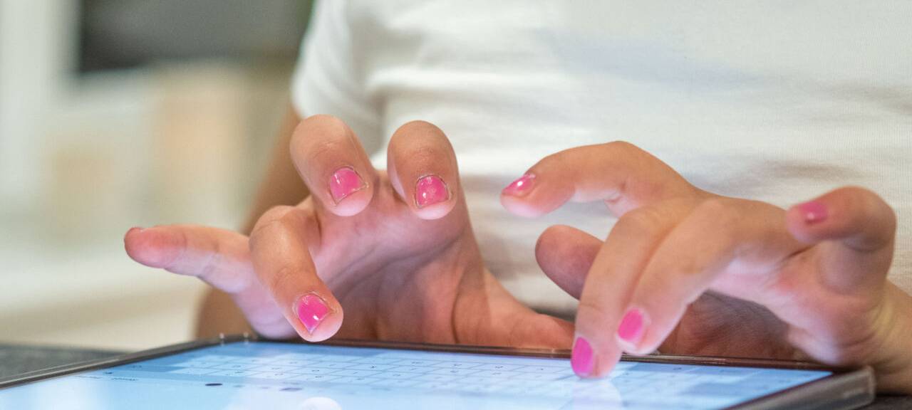 Eine Person tippt auf einem Tablet etwas ein.