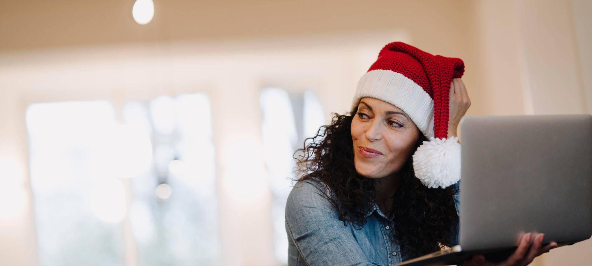 Eine Frau mit Weihnachtsmütze am Laptop