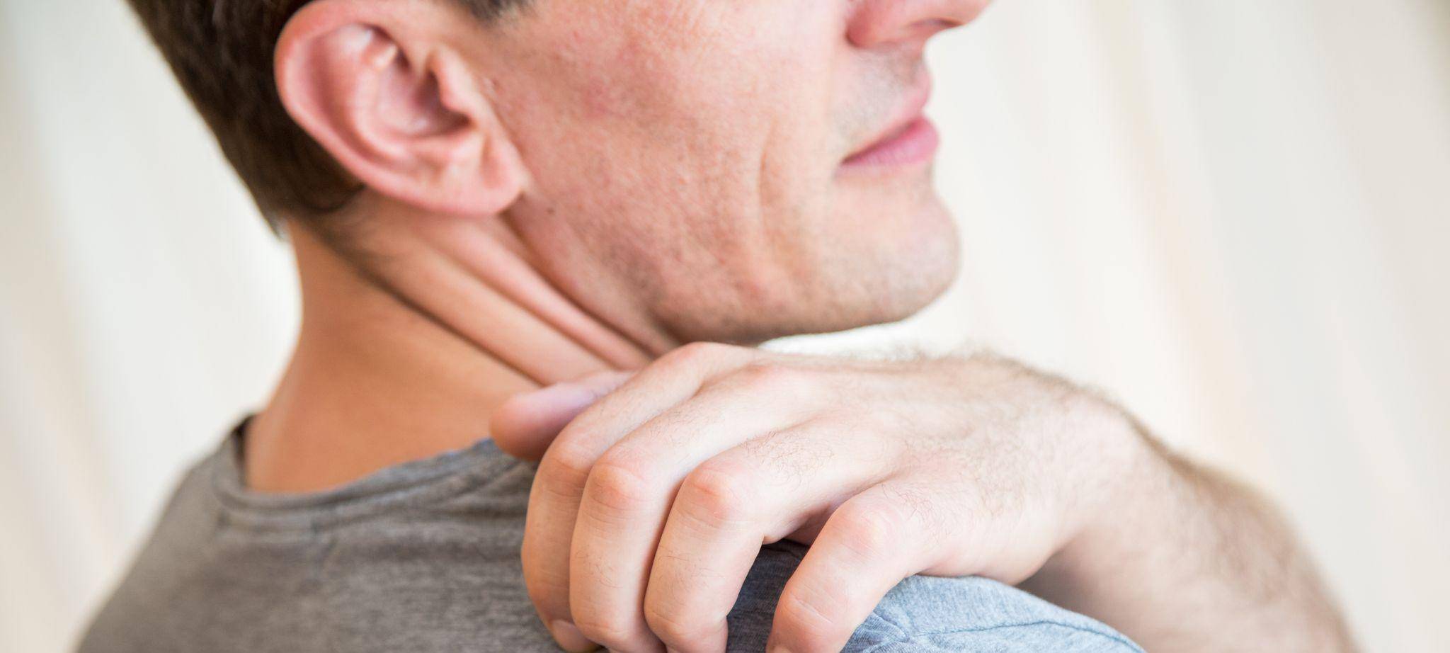 Mann kratzt sich an der Schulter