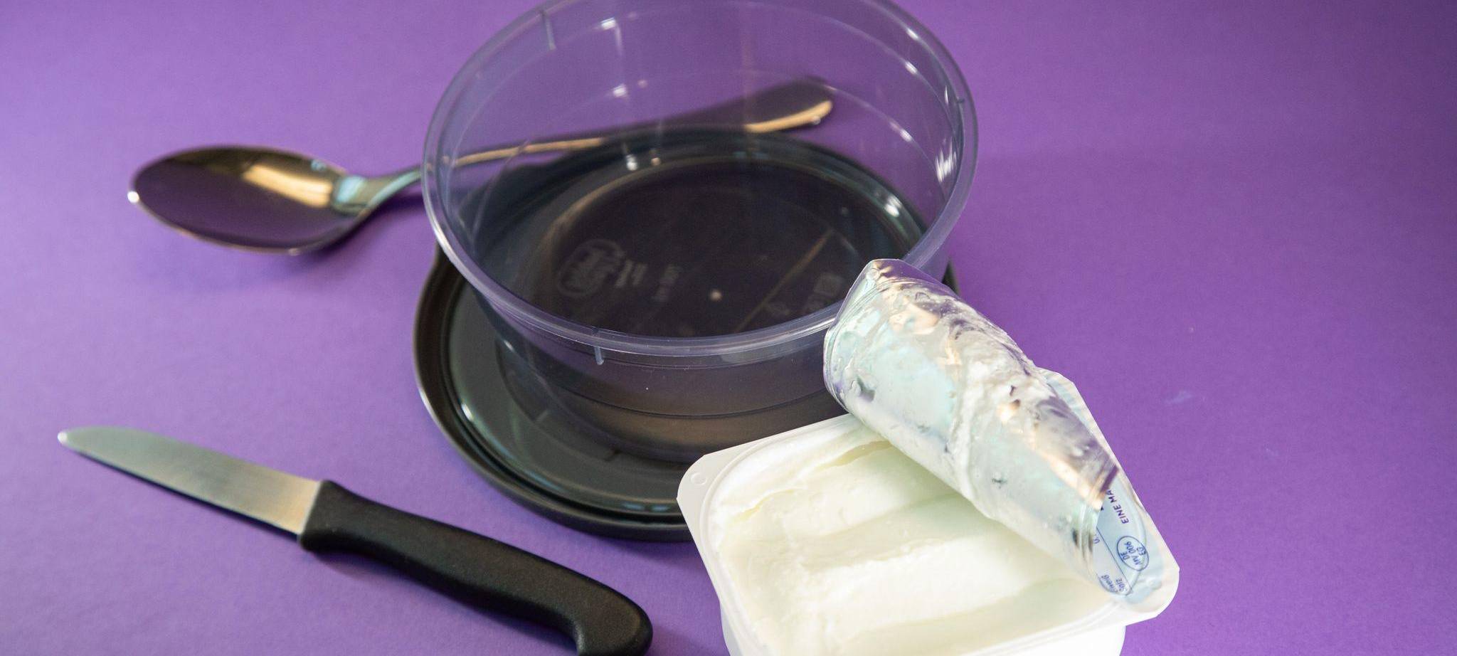 Ein Becher Quark steht neben einer Schüssel