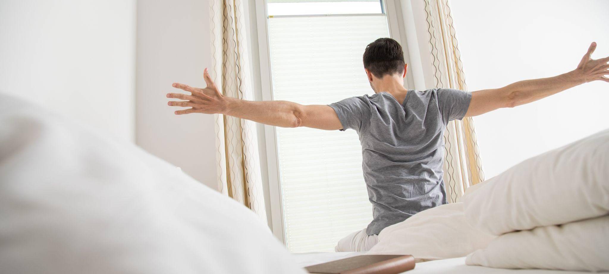 Ein Mann streckt sich am Morgen nach dem Aufwachen