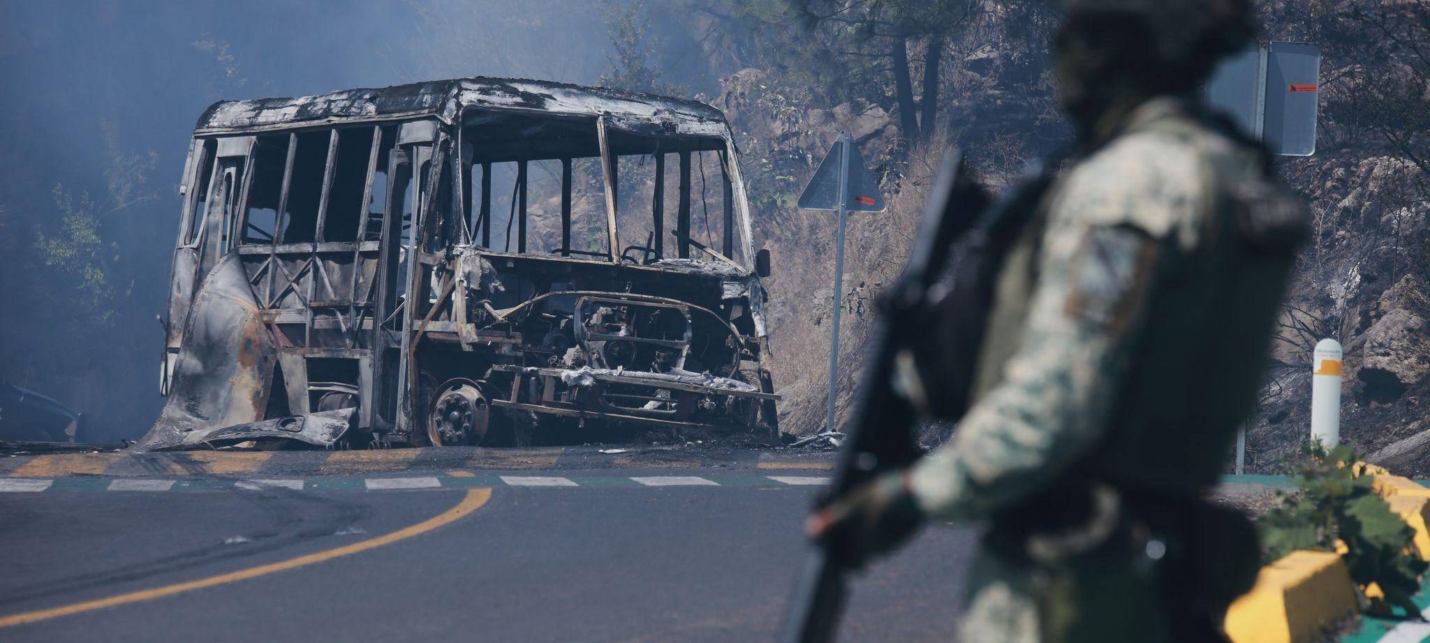 Ein Soldat steht in Cointzio neben einem ausgebrannten Bus