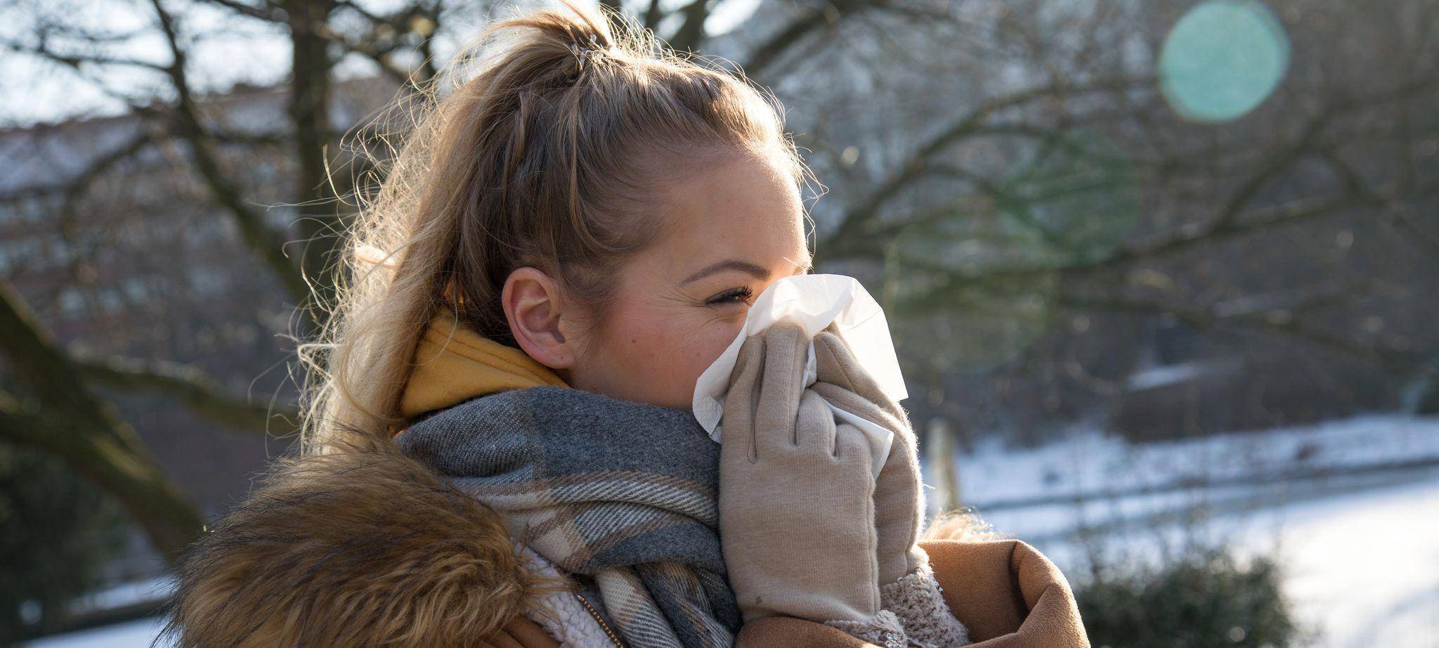 Frau putzt sich im Park die Nase