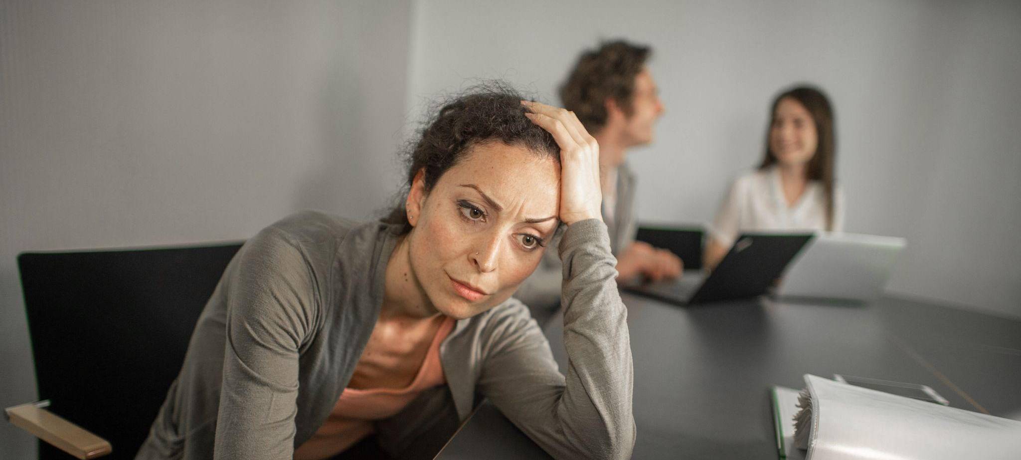 Frau sitzt grübelnd vor ihrem Laptop im Büro