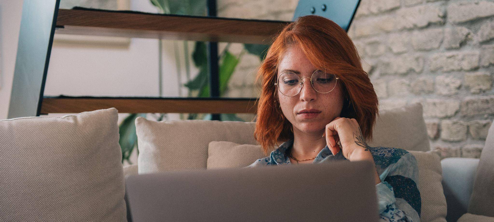 Frau schaut nachdenklich auf einen Laptop