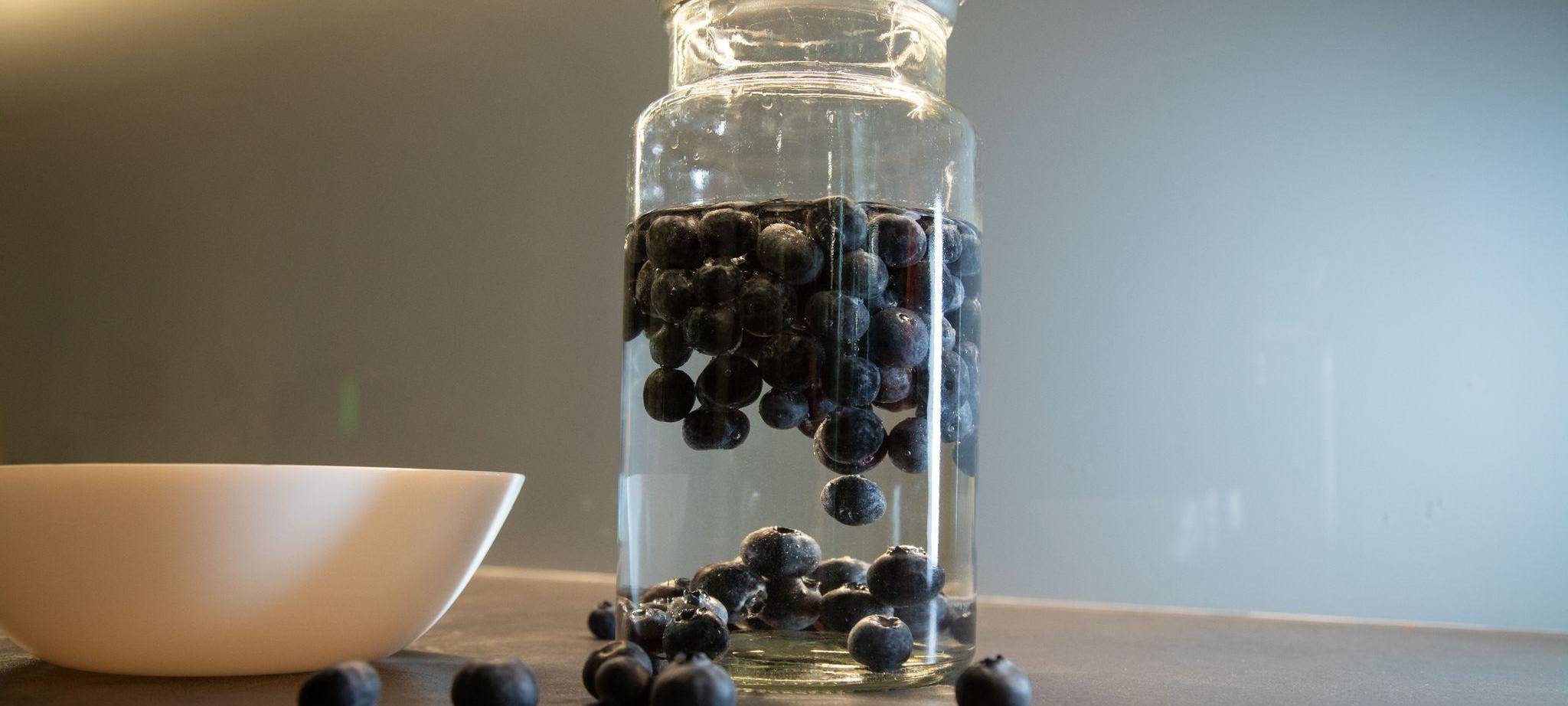 Blaubeeren schwimmen in einem Glas mit Wasser